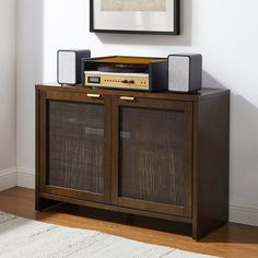 a wooden cabinet with speakers and a radio on top in a room next to a painting