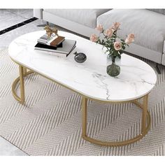 a white marble coffee table with gold legs and flowers in a vase on the top