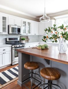 a kitchen with white cabinets and wooden counter tops