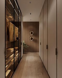 an empty hallway with wooden floors and glass doors leading to the closets that are full of clothes