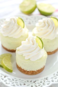 three lime cheesecakes on a white plate with lime wedges around the edges