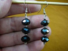 a pair of black beaded earrings is being held by a person's hand