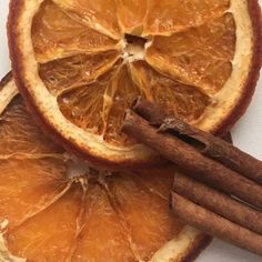 an orange cut in half with cinnamon sticks