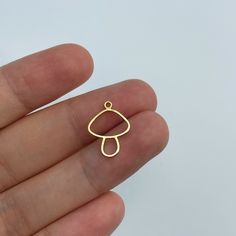 a person's hand holding a tiny gold earring in the shape of an umbrella