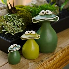 three ceramic birds sitting next to each other on a wooden table with plants in the background