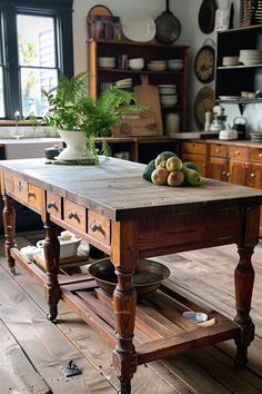 an old wooden table with fruit on top in a room filled with pots and pans