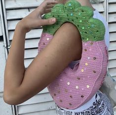 a woman holding onto a crocheted bag with sequins on the back