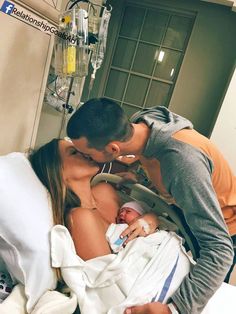 a man and woman kissing in bed next to a baby