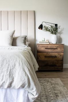 a bed with white linens and pillows in a small room next to a dresser