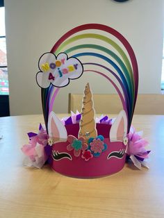 a paper crown sitting on top of a wooden table next to a rainbow shaped sign