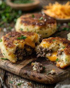 two cheeseburger patties on a cutting board with other food items in the background