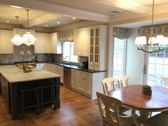 a large kitchen with an island in the middle and white cabinets on both sides, along with hardwood flooring