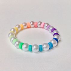 This is a clay bead stretch bracelet. This clay bead bracelet has rainbow clay beads along with white pearls. Clay Bead Bracelet Pearl, Clay Bead Bracelet Ideas Rainbow, Clay Bead Bracelet Ideas No White, Clay Beads Idea, Bracelet Ideas With Clay Beads, Macaroni Bracelet, Bracelet Buisness, Clay Beads Bracelet Ideas