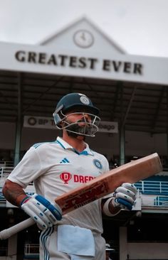 a man holding a cricket bat in front of a building with the words greatest ever written on it