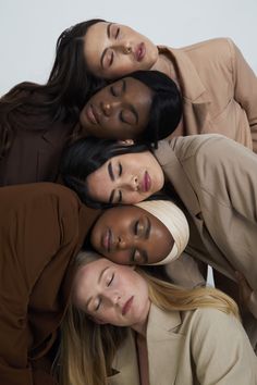 four women are standing together in a circle and one is wearing a tan coat, the other has her head on top of another woman's shoulders