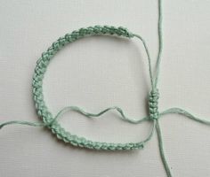 a close up of a piece of green string on a white surface with a knot in the middle