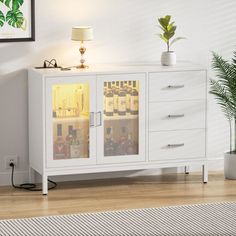 a white cabinet with glass doors in a living room next to a potted plant