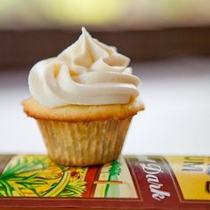 a cupcake with white frosting sitting on top of a box