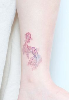 a small tattoo on the ankle of a woman's foot with a pink and blue fish