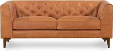 a tan leather couch sitting on top of a white floor