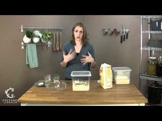 a woman standing in front of a counter with cheese on it and other items around her