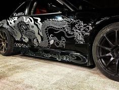 a black car with white dragon decals on it