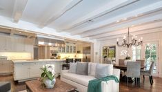 a living room filled with furniture and a wooden table in front of a kitchen area