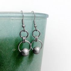 Shown on a teal vase, these earrings are made from thick stainless steel rings of varying widths.  The bottom rings which are the widest at 1/2" in diameter each feature a matte silver stainless steel bead.  These earrings are great for sensitive ears as each french hook earring wire is stainless steel as well.Since these earrings are stainless steel you will not have to worry about tarnishing or polishing.  These beauties will look the same in 20 years as they do today. These earrings hang appr