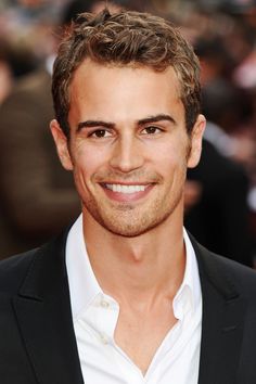 a smiling man in a black suit and white shirt