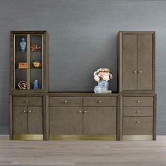 a vase with flowers on top of it next to a bookcase and cabinets in an empty room