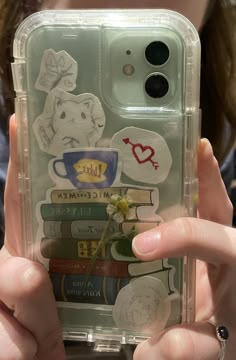 a person holding up a phone case with stickers on it