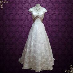 a white wedding dress on display in front of a purple wall with an ornate pattern