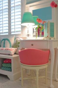 a pink chair sitting in front of a white desk with a lamp on top of it