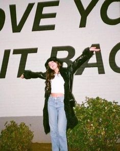 a woman standing in front of a sign with her arms outstretched