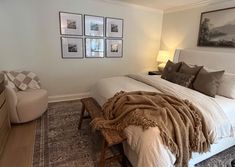 a bedroom with a bed, chair and pictures on the wall