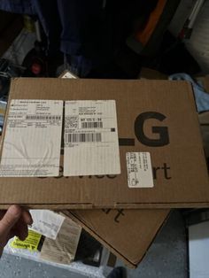 a person holding up a box with the letter g on it's front and side