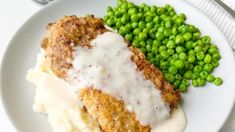 a white plate topped with meat, mashed potatoes and peas