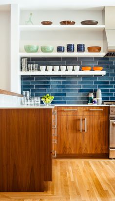 a kitchen with wooden floors and blue tile backsplash