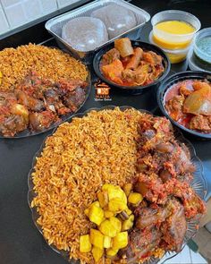 several plates filled with different types of food on a black counter top next to orange juice