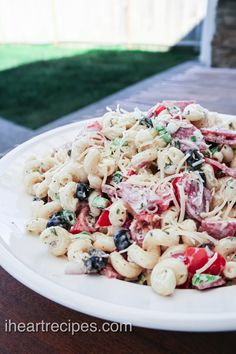 a white plate topped with pasta salad on top of a wooden table