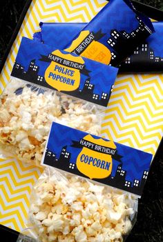 three bags of popcorn sitting on top of a yellow and blue table cloth next to each other