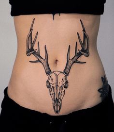 a woman's stomach with a deer skull and antlers tattoo on the side