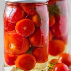 tomatoes are in a jar with water on the table