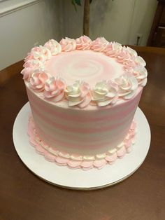 a pink and white striped cake sitting on top of a table