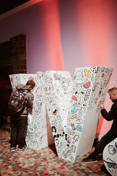 two people sitting on the floor next to large letters with stickers all over them