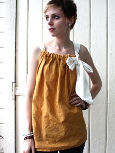 a woman standing in front of a white door wearing black pants and a yellow top