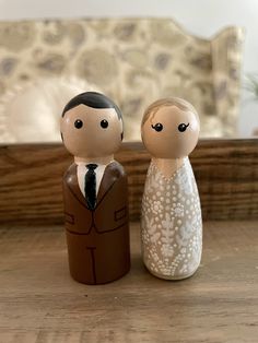 two wooden figurines, one in a suit and the other in a dress