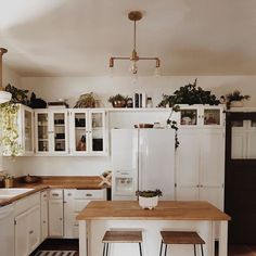 a kitchen with white cabinets and wooden counter tops, two stools in front of the island