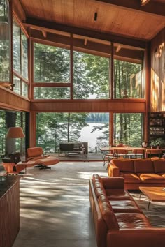 a living room filled with lots of furniture and large windows overlooking the trees in the background