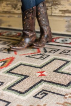 a woman standing on top of a rug wearing cowboy boots